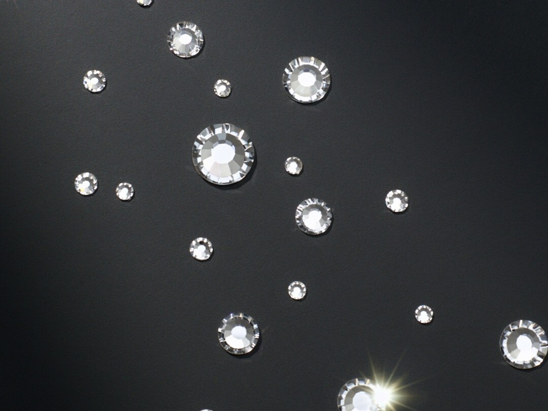 Preciosa MAXIMA crystals scattered on black, catching light