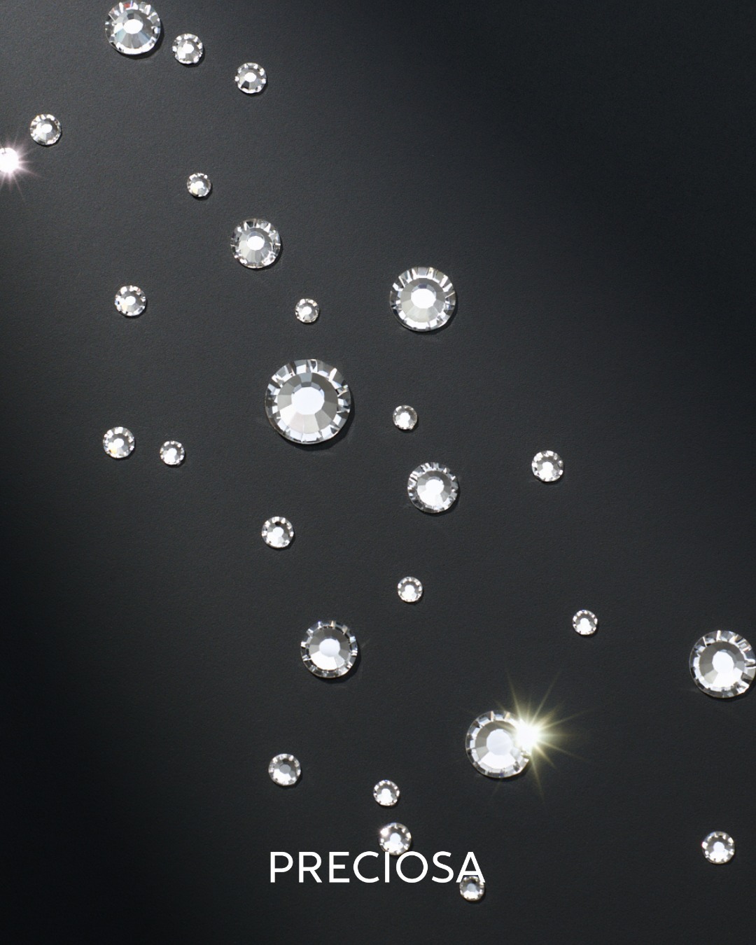 Individual Preciosa crystals scattered on a black background showing facet detail